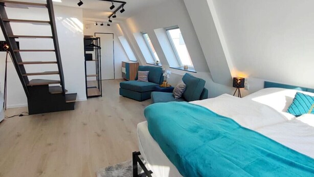Une chambre de style loft moderne, dotée d’une lucarne, d’un escalier intégré, d’un canapé et d’un lit.