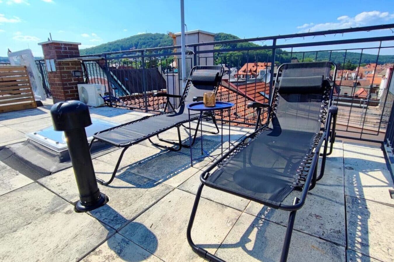 Una terraza en la azotea con dos tumbonas, una mesita y una planta en maceta.