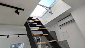 Un intérieur moderne agrémenté d’une verrière, d’un escalier et d’un appareil de climatisation.