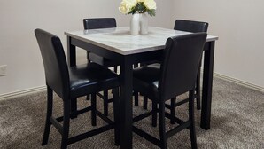 Ein Konferenzraum mit einem Marmortisch, vier schwarzen Stühlen, einer Vase mit weißen Blumen und zwei abstrakten Bildern an der Wand.