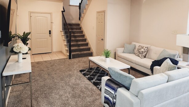 Ein Wohnzimmer mit einer Couch, einem Couchtisch und einer Treppe.
