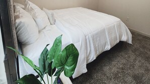Ein Schlafzimmer mit einem Bett, einem Deckenventilator, einem an der Wand montierten Fernseher und einem Blumentopf auf dem Nachttisch.