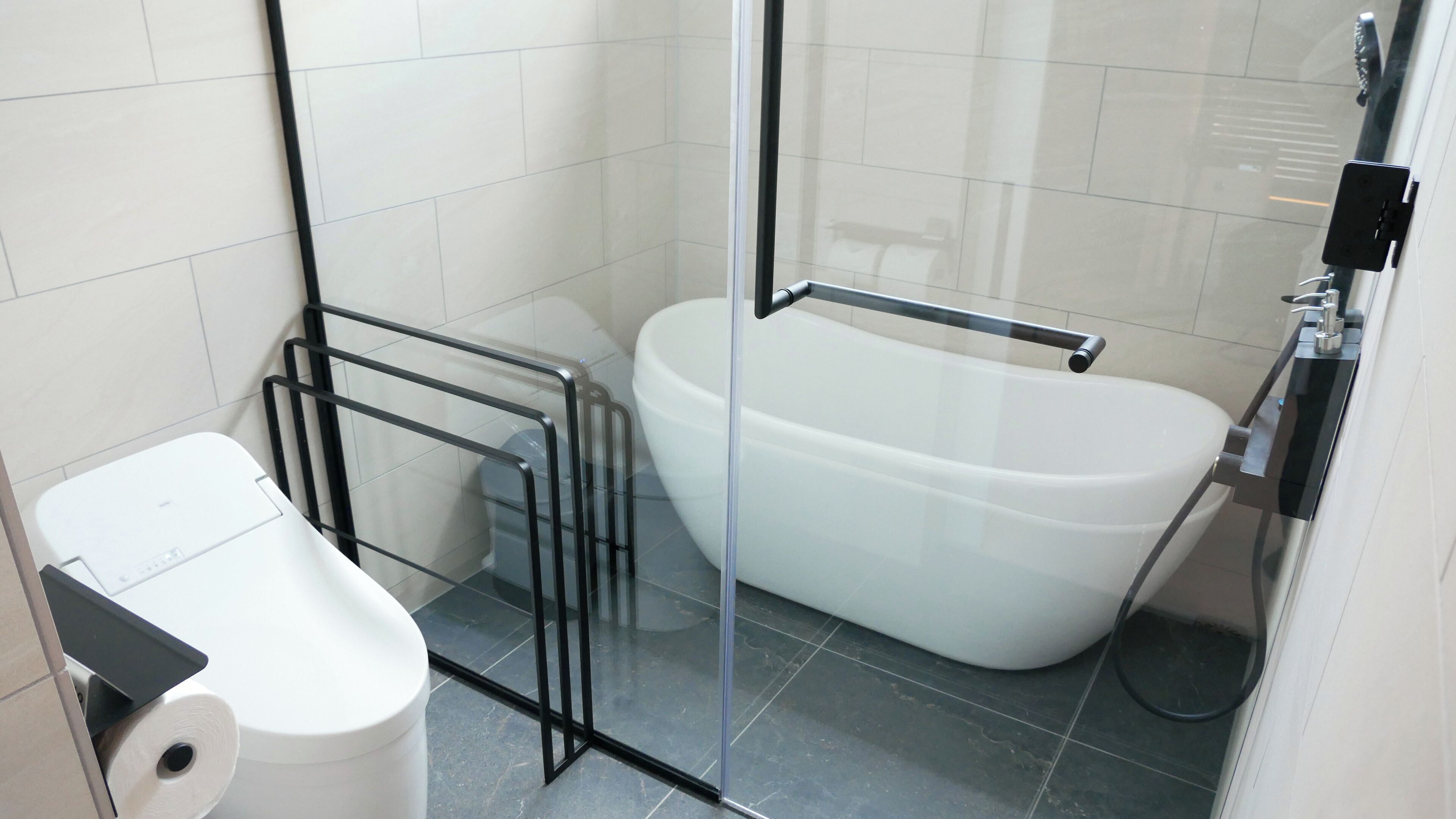 Un baño moderno con cabina de ducha de vidrio, una bañera blanca y un inodoro.