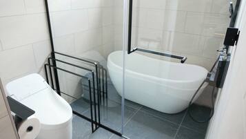 Un baño moderno con cabina de ducha de vidrio, una bañera blanca y un inodoro.