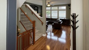 Un vaste espace de vie agrémenté d’un escalier en bois, d’un ventilateur de plafond et d’un coin salon avec un tapis.