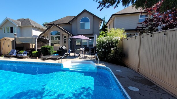 Un jardin avec une piscine, des chaises longues et un patio couvert.