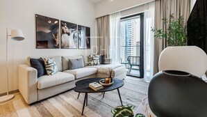 A modern living room with a sofa, a coffee table, and a large window with a view of high-rise buildings.