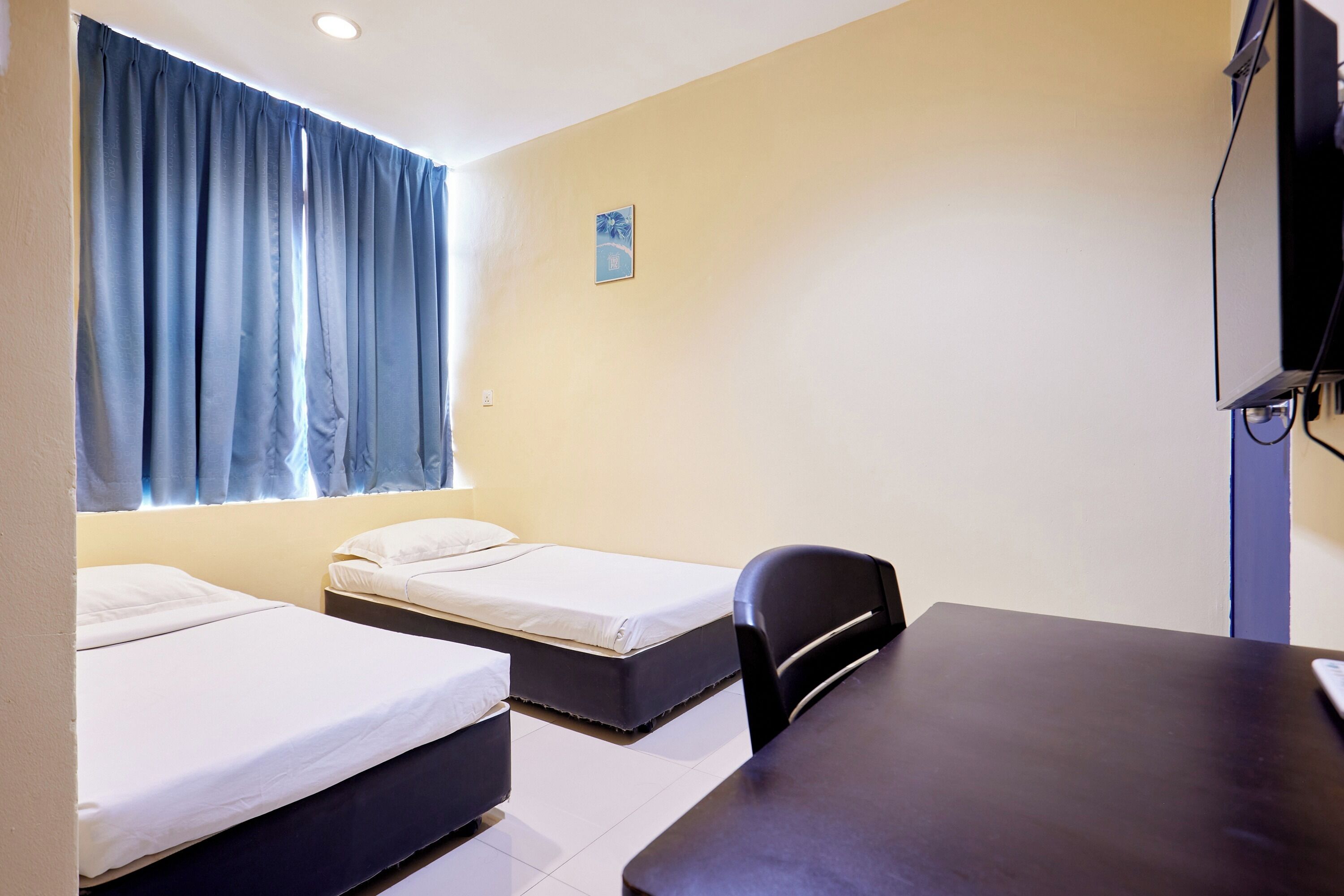 A room with two beds, a desk, and a TV.