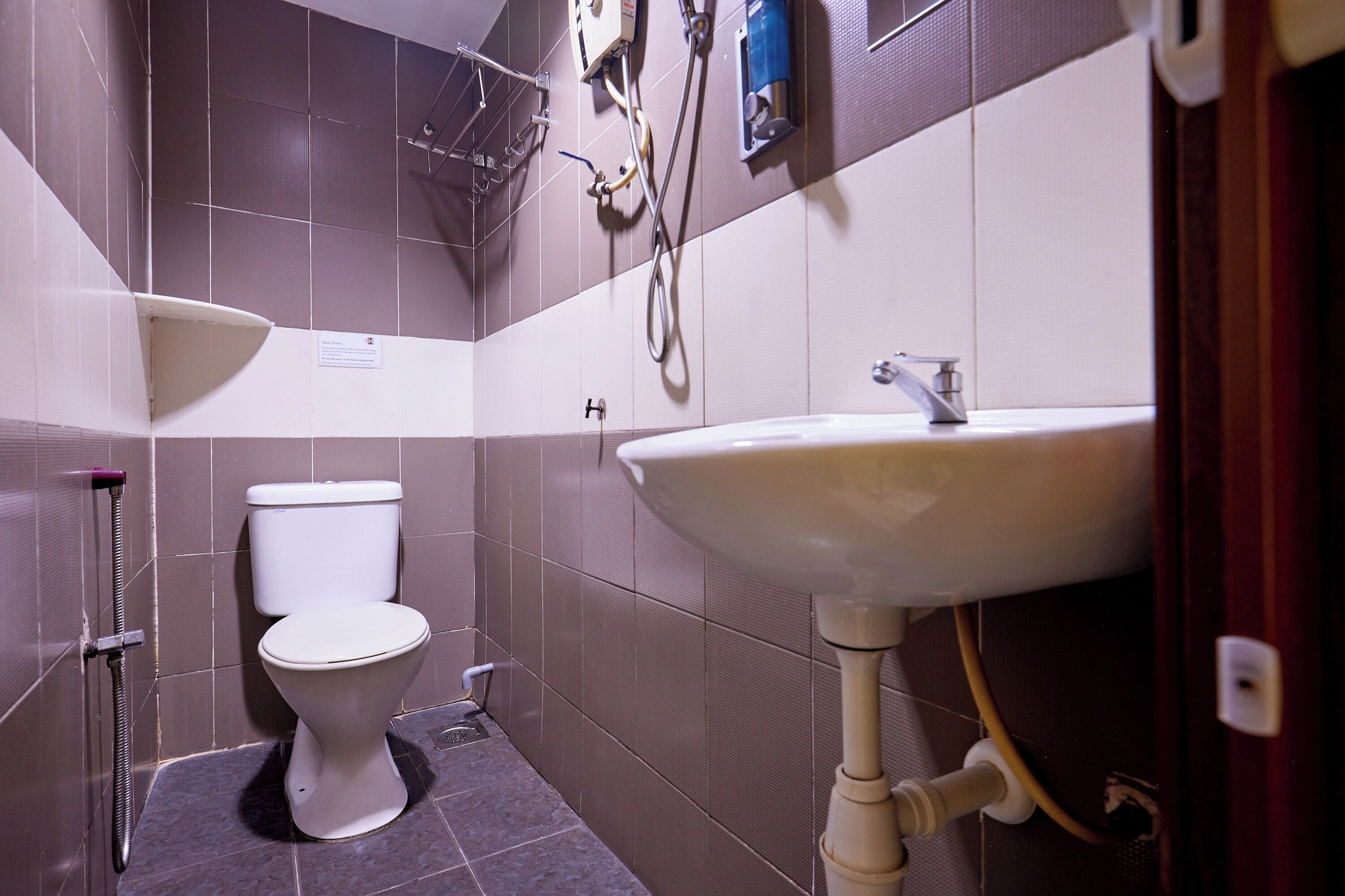 A bathroom with a white toilet, a pedestal sink, and a shower area.