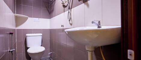 A bathroom with a white toilet, a pedestal sink, and a shower area.
