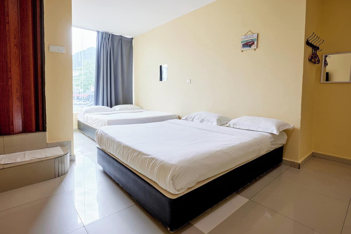 A hotel room with two beds, a large window with curtains, a wooden door, and a mirror on the wall.