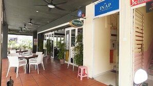 Un couloir d’hôtel avec des ventilateurs de plafond, une enseigne PappaRich et une enseigne pour l’hôtel InAP.
