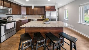 A modern kitchen with dark wood cabinets, stainless steel appliances, and a large island with bar stools.