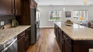 A modern kitchen with dark wood cabinets, granite countertops, and stainless steel appliances.