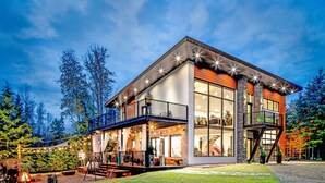 Een modern huis met een ruim balkon, een overdekte veranda en een trap naar een hoger niveau.