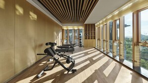 Een moderne sportschool met trainingsapparatuur, grote ramen en een houten plafond.