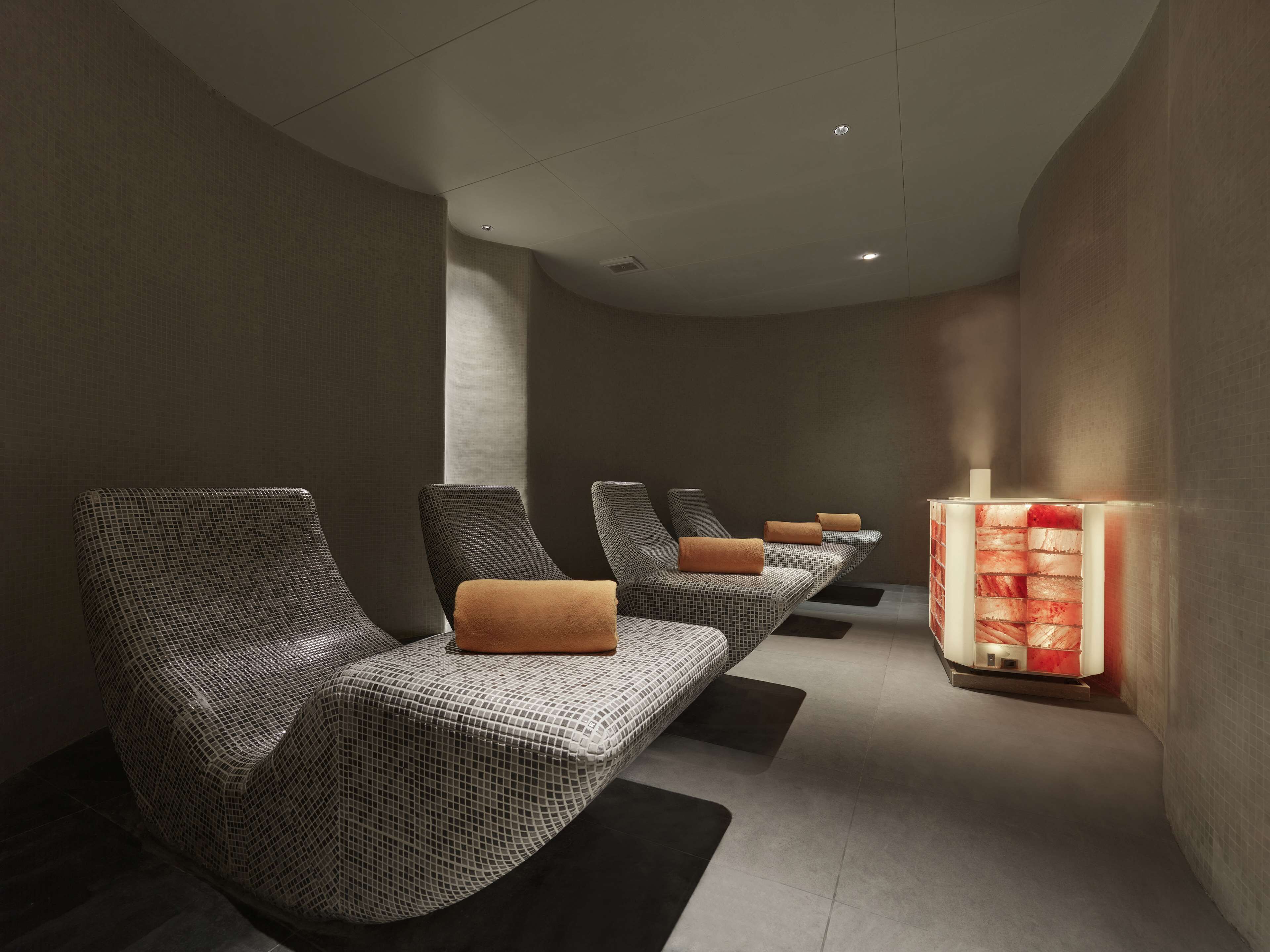 A spa room with four massage chairs, each with a towel and a footrest.