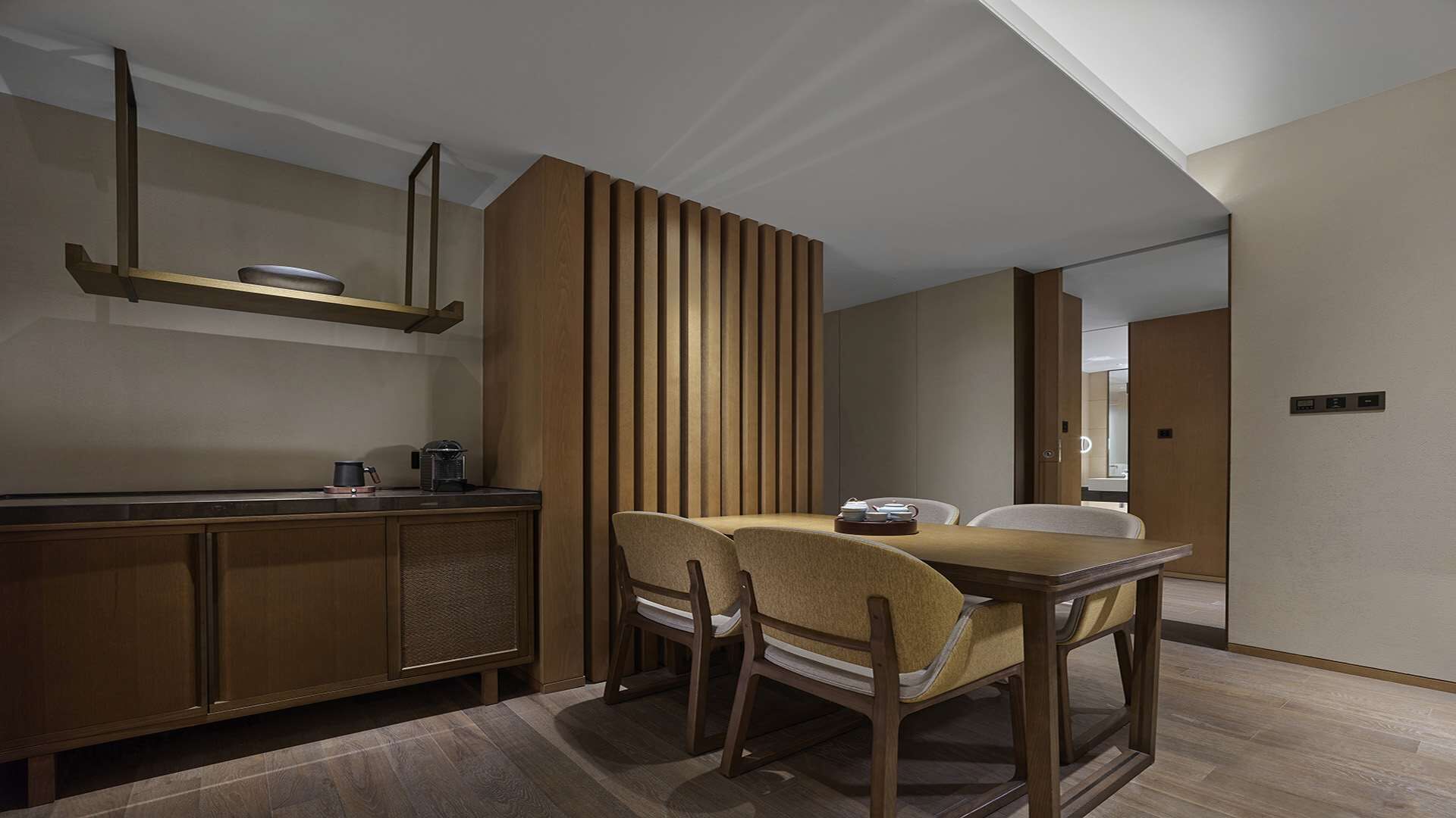 A modern kitchen with wooden cabinets, a dining table with chairs, and a built-in vertical wooden panel.