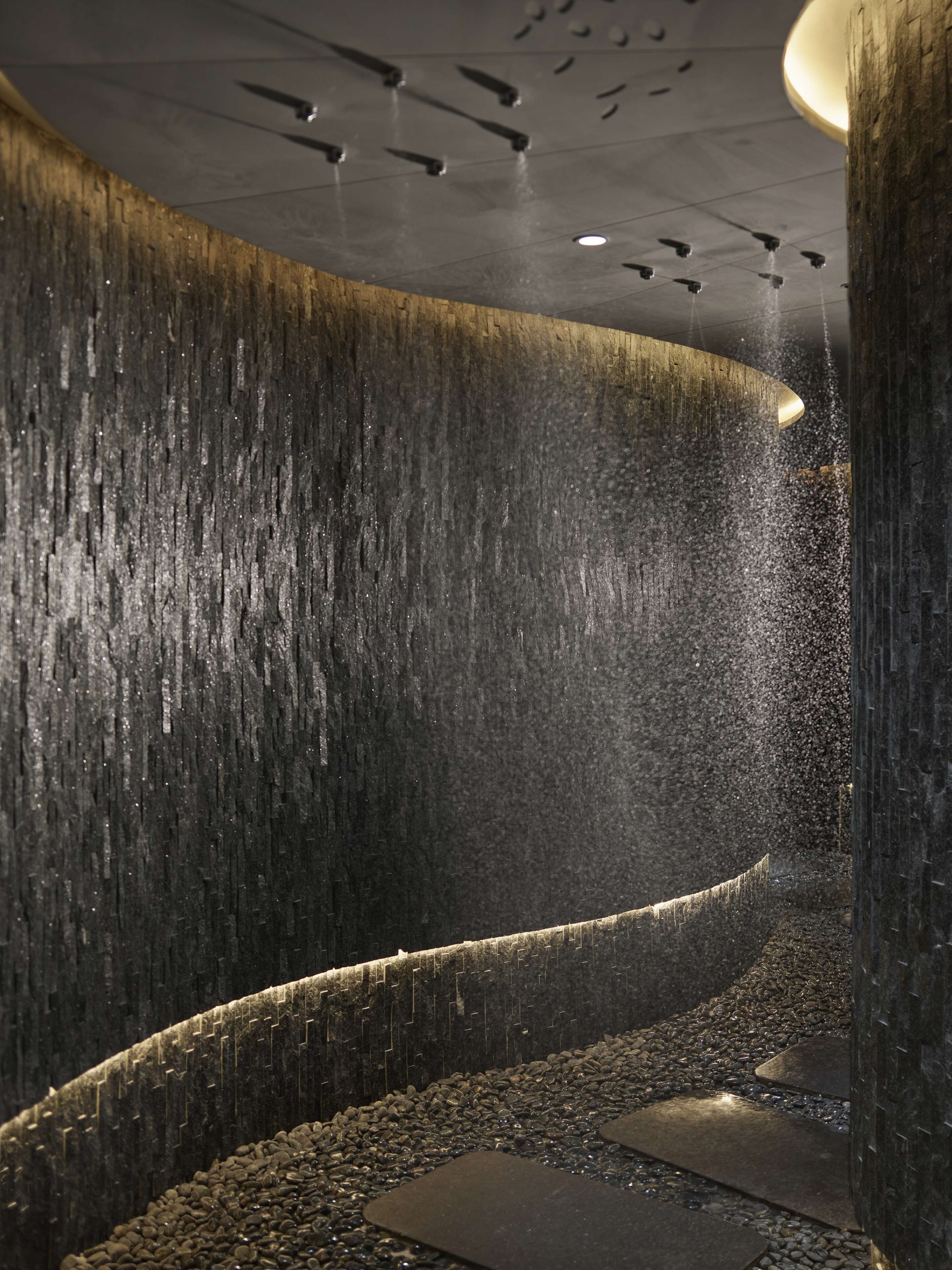 A modern interior with a curved wall, a water feature, and a ceiling with recessed lighting.