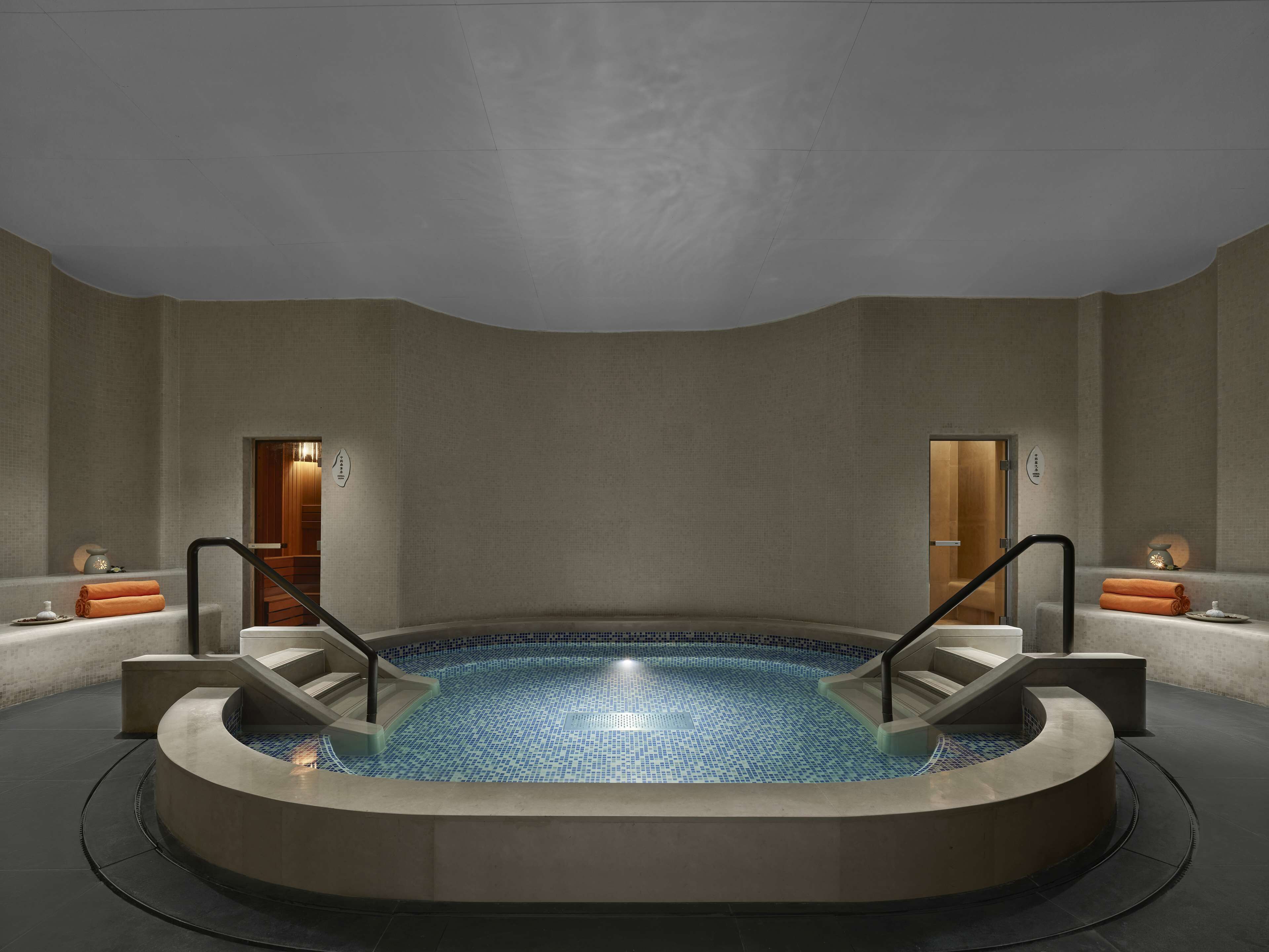 A modern spa area with a circular hot tub, two wooden doors, and a minimalist design.