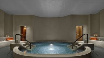 A modern spa area with a circular hot tub, two wooden doors, and a minimalist design.