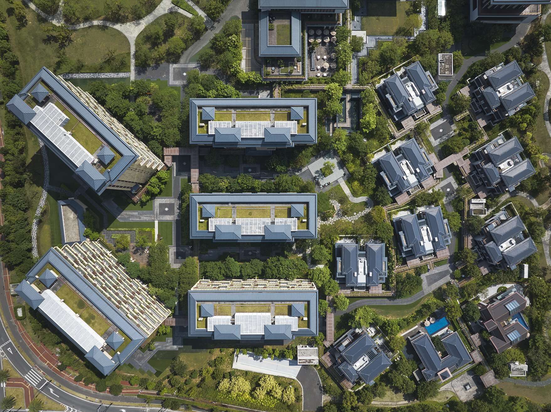 Vista aérea de un campus moderno con edificios rectangulares, zonas verdes y una piscina.