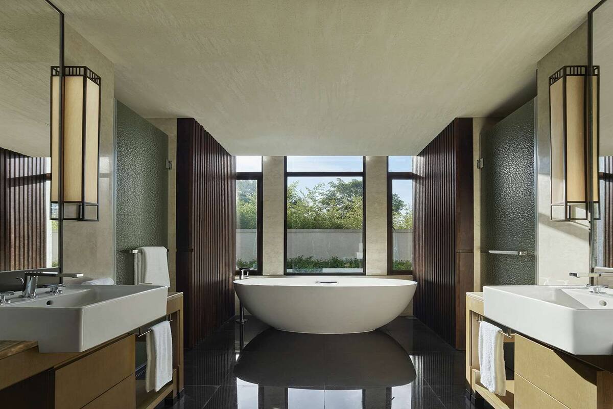 Une salle de bain moderne avec une baignoire sur pieds, deux vasques et de grandes fenêtres.