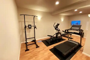 Work out in comfort with a home gym featuring a pull-up bar, elliptical machine, and treadmill.