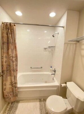 Bathroom features a bathtub, toilet, and shower area with a glass door.