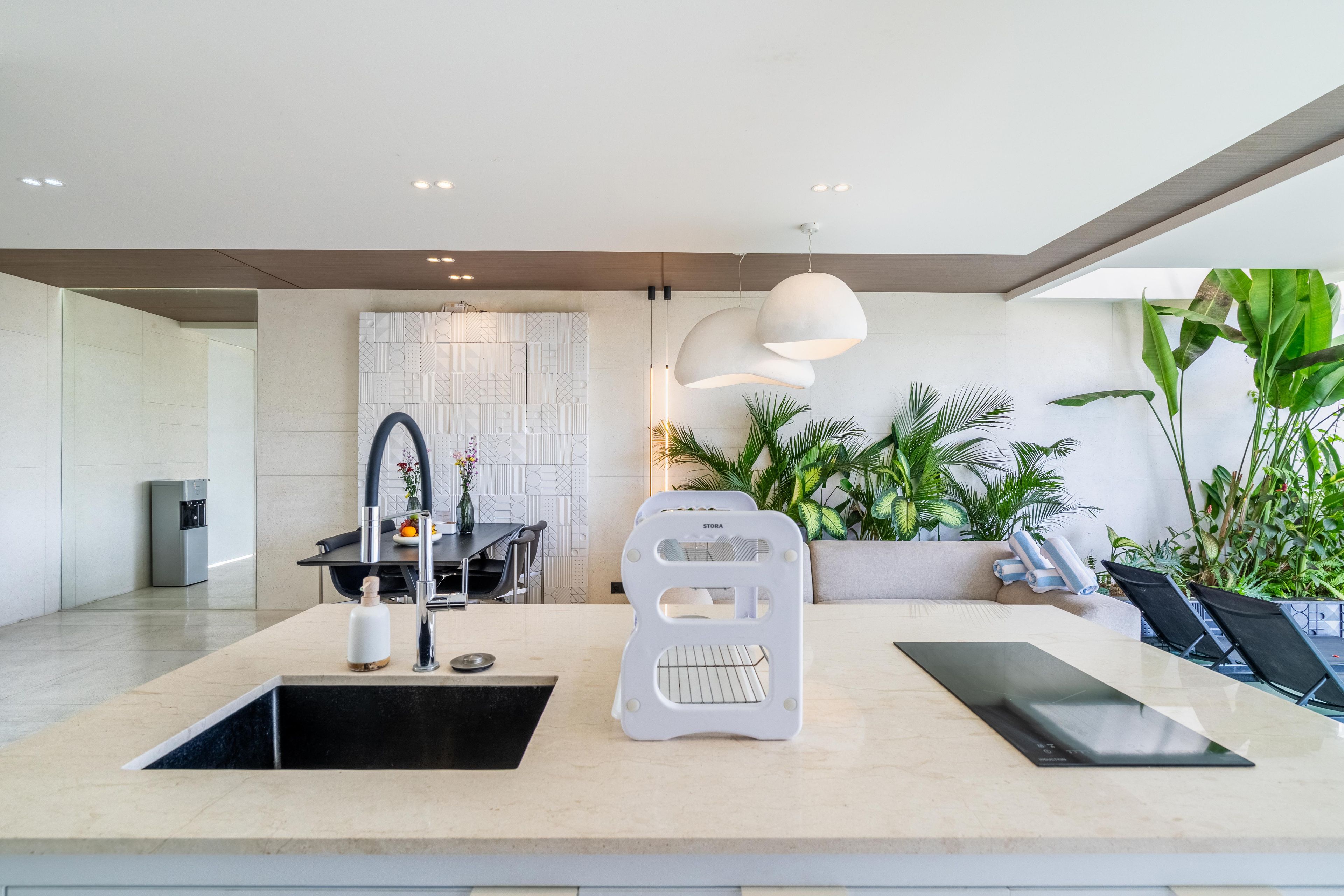 A modern kitchen with a central island, a built-in water dispenser, and a seating area with a sofa and chairs.