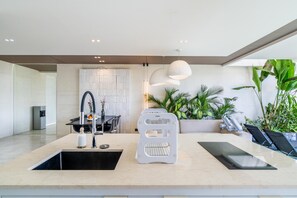 A modern kitchen with a central island, a built-in water dispenser, and a seating area with a sofa and chairs.