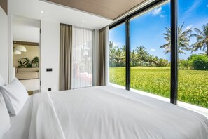 Un dormitorio con una cama grande, vistas a un campo verde y una ventana con cortinas.