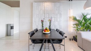 A modern dining area with a long table, black chairs, and a decorative wall with geometric patterns. - Green Flow Villa 2 with Private Pool in Ubud (Ubud)