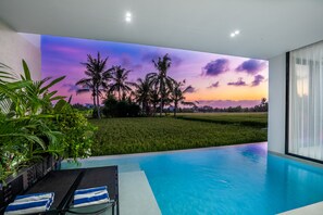 Ein moderner Poolbereich mit Blick auf ein Feld und Palmen.