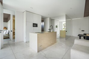 A modern kitchen with a central island, white cabinetry, and a microwave.