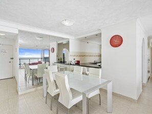 Una cocina moderna con comedor, un reloj rojo y vistas al mar.