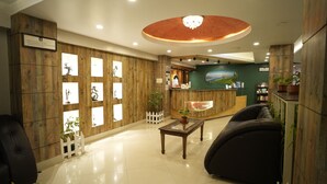 Un hall de hotel con paneles de madera, un mostrador de recepción, una araña y una mesa de centro.