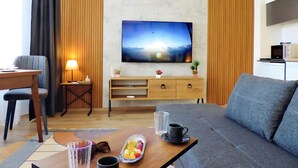 Moderni olohuone, jossa on litteänäyttöinen televisio, puuhuonekalut, sohva ja ruokailutila.