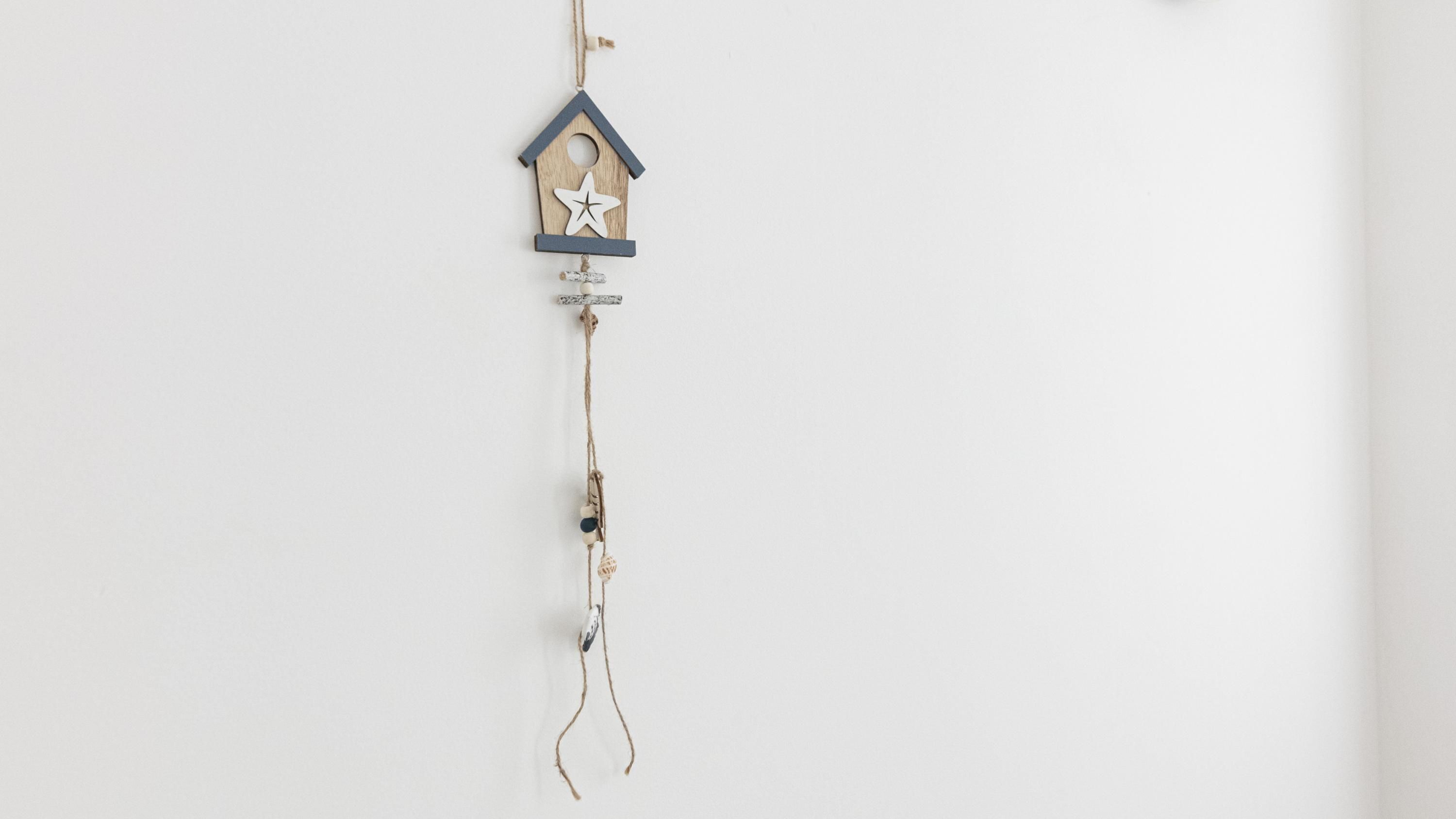 A wooden birdhouse with a star decoration hanging from a string.