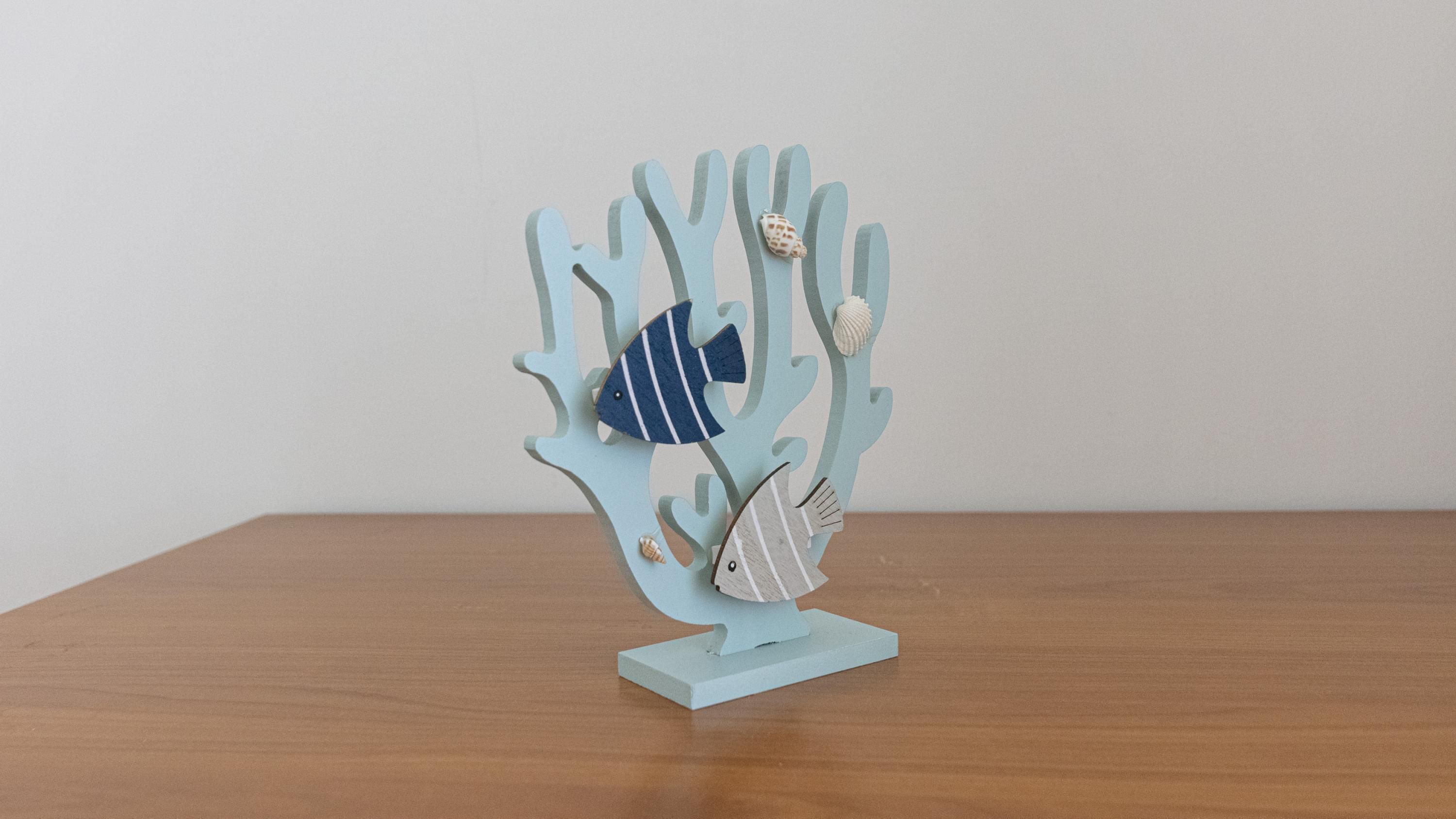 A wooden table with a decorative coral structure featuring fish and seashells.