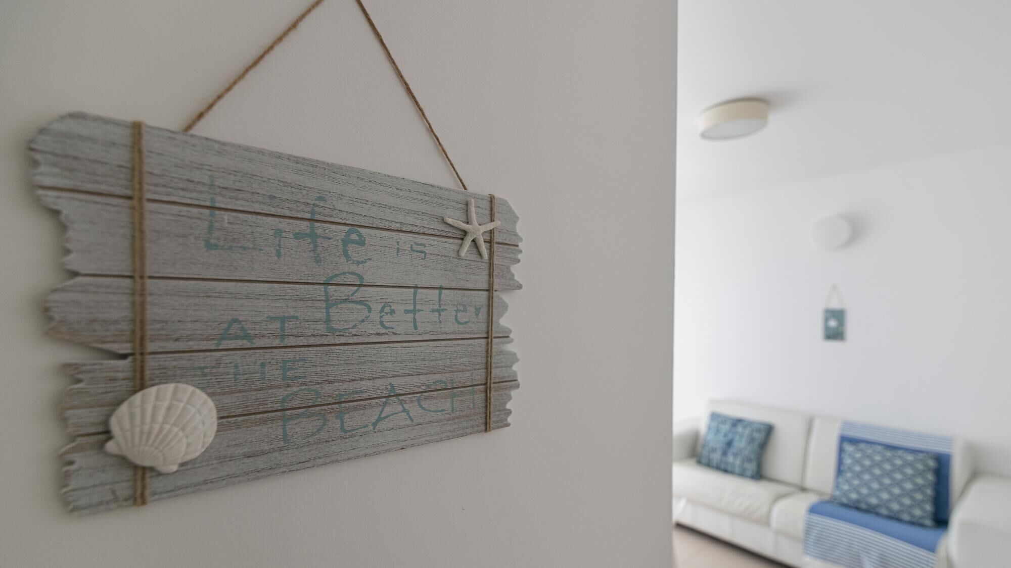 A rustic wall decoration with the phrase "Life is Better at Home" and a starfish.