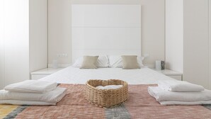 Un dormitorio moderno con una cama grande, dos mesitas de noche, un cabecero y una cesta tejida en el suelo.