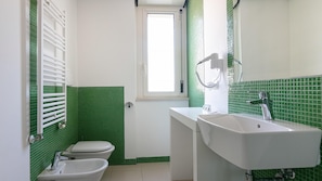 A bathroom with a toilet, bidet, sink, and a window. - Residenza Excelsior 709 (Vasto)