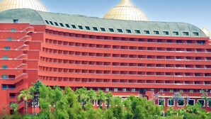 Een hotel met meerdere verdiepingen, een opvallende rode gevel en grote gouden koepels.