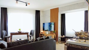 Een moderne woonkamer met een bank, een eettafel, een televisie en een keuken met een fornuis.