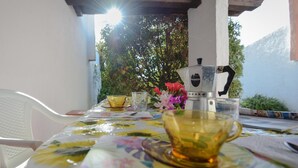 A table with a coffee maker, cups, and a floral tablecloth. - Villa Chiara in Costa Rei (Muravera)