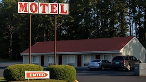 A motel with a red roof, two cars parked in front, and a sign that says "MOTEL" and "ENTER". - Courtland Inn By Townhouse Franklin VA US 58 (Courtland)