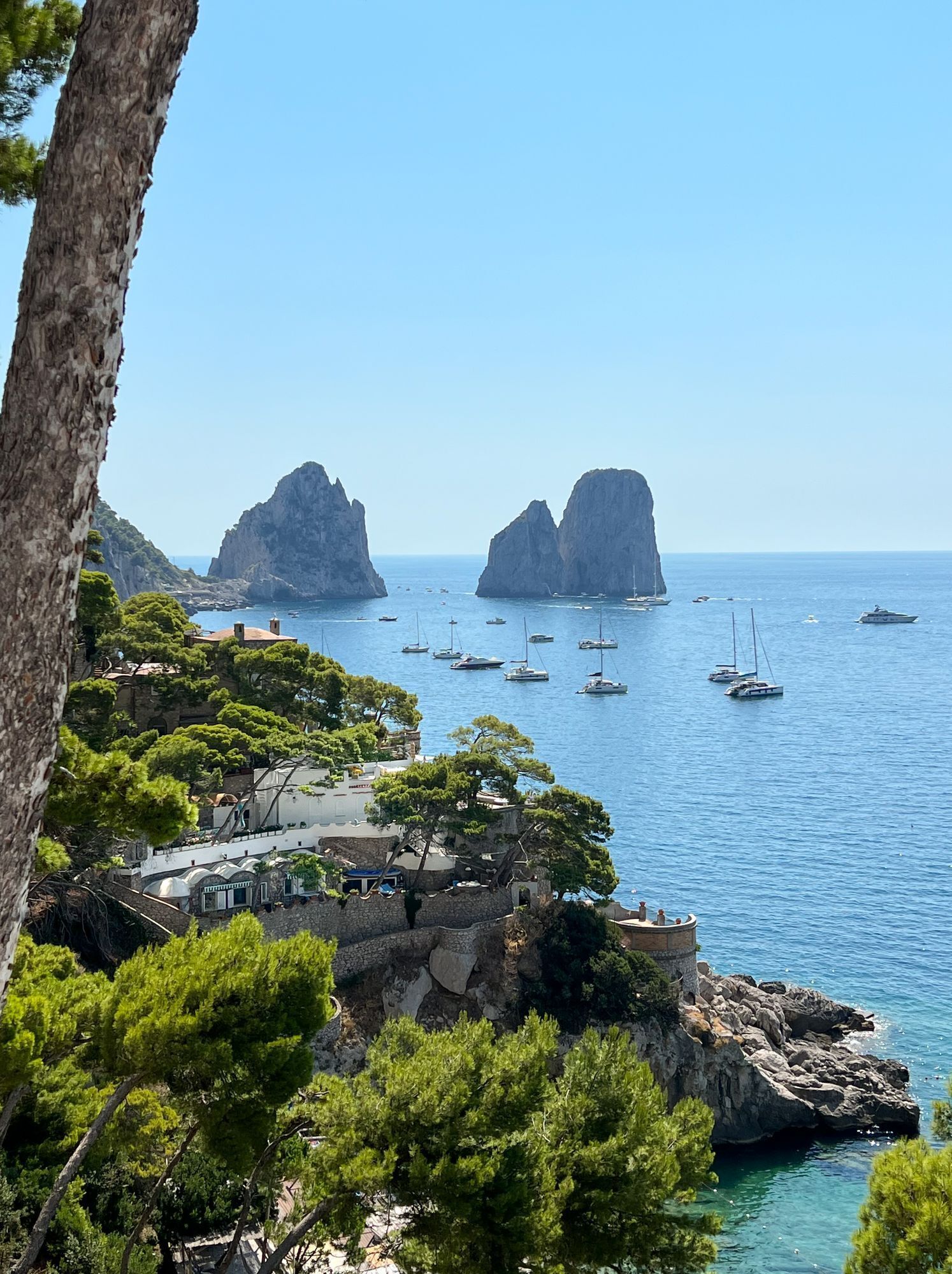 Blick auf die Küste mit schroffen Klippen, klarem, blauem Meer und Booten.