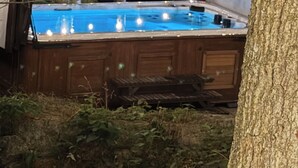 An outdoor swimming pool with string lights, surrounded by trees. - STUNNING LARGE CHALET COTTAGE IN MUSKOKA (Coldwater)