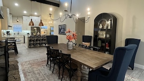 A spacious dining area with a large wooden table, dark chairs, and a chandelier.
